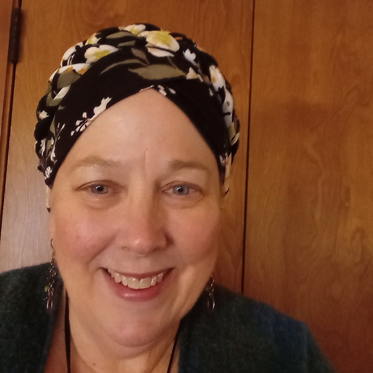 Person wearing a patterned headscarf on a wooden floor
